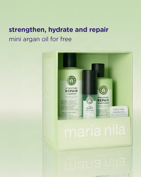 Maria Nila haircare set in a pale green box, featuring a shampoo bottle, a conditioner bottle, and a small free mini argan oil packet, with promotional text above on a matching pale green background.