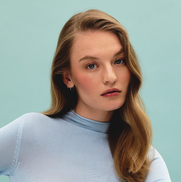 Model with dark blonde hair against blue background
