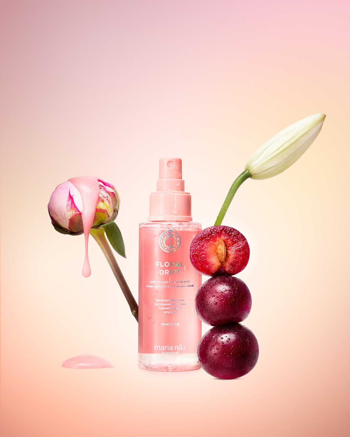 Pink bottle of Maria Nila Floral Drift hair mis with flowers and plums on a gradient background