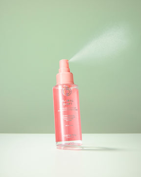 Pink spray bottle of Maria Nila Floral Drift hair mist on a light green background